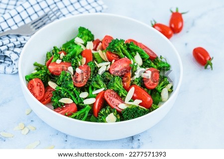 Broccoli salad with cherry tomatoes and almonds in a white bowl. Vegan detox recipe.