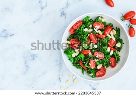 Broccoli salad with cherry tomatoes and almonds in a white bowl, top view. Vegan detox recipe.