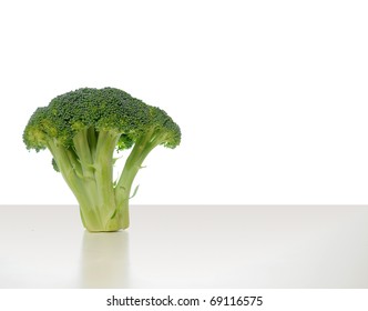 Broccoli Vegetable Standing On A White Shiny Table Isolated On White Background.