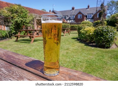 Brockenhurst, Hampshire, England - 05.27.2021 : A Cool Pint Of Beer On Pub Garden Table At The Huntsman Of Brockenhurst. A 13th Century Inn. Popular Summer Beer Garden Of New Forest Pub