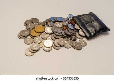 Brockville, Ontario, Canada - October 29, 2016. Canadian coins flowing from a leather pouch on the right side on a white background.