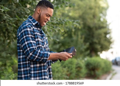 I'm Broke. Frustrated black man holding his empty wallet, looking shocked, copy space, selective focus