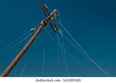 Broke Power Line Pole With Multiple Broken Cables Against Clear Blue Sky