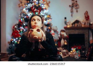 
Broke Woman Holding a Piggy Bank Regretting Christmas Spendings. Desperate girl feeling sad about spending too much money on holidays
