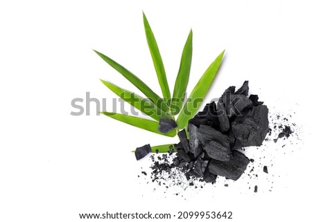 Broken activated charcoal with bamboo leaf isolated on white background. Top view.