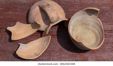 Broken Antique Clay Pot On A Wooden Table In The History Museum. Pieces Of Old Clay Pot Or Traditional Jar
