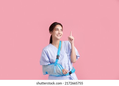 Broken Arm,  Beautiful Young Asian With Happy Smiling Woman On Pink Background, Healthcare Concept, Accident, Insurance, Life Insurance, Wellness, Hospital.