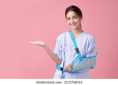 Broken Arm,  Beautiful Young Asian With Happy Smiling Woman On Pink Background, Healthcare Concept, Accident, Insurance, Life Insurance, Wellness, Hospital.