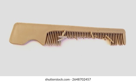 A broken beige plastic comb with missing and bent teeth, isolated on white background. Symbol of damage, imperfection, or old daily item. Close-up object photo.