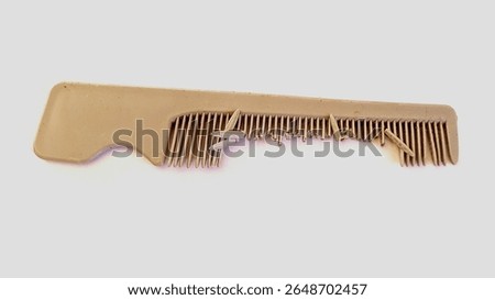 A broken beige plastic comb with missing and bent teeth, isolated on white background. Symbol of damage, imperfection, or old daily item. Close-up object photo.