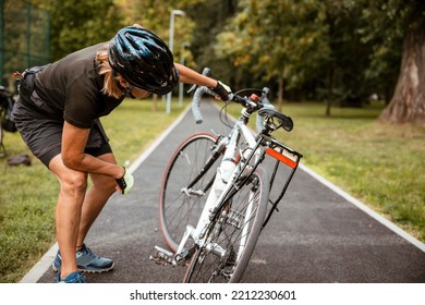 Broken Bike While Riding In The Park. Senior Female Have Trouble With Bicycle Outdoor. Sporty Mature Woman Cyclist Fixing Her Bike