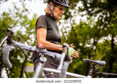 Broken Bike While Riding In The Park. Senior Female Have Trouble With Bicycle Outdoor. Sporty Mature Woman Cyclist Fixing Her Bike