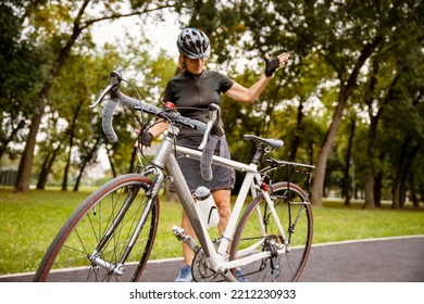 Broken Bike While Riding In The Park. Senior Female Have Trouble With Bicycle Outdoor. Sporty Mature Woman Cyclist Fixing Her Bike