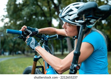 Broken Bike While Riding In The Park. Senior Female Have Trouble With Bicycle Outdoor. Sporty Mature Woman Cyclist Fixing Her Bike