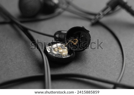 Broken black headphones on a dark gray background. Damaged crushed earphones. Cheap faulty electronic devices concept
