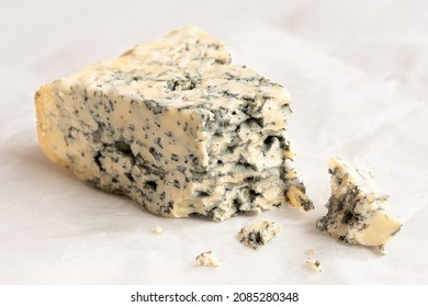 Broken Blue Cheese Wedge With Crumbles On Wax Paper..