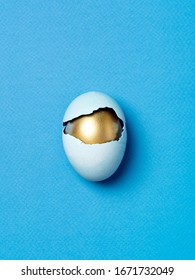 Broken blue egg and golden egg inside on a blue background. Concept of intrinsic values or hidden talents. Easter minimalist banner. Happy Easter day wallpaper.