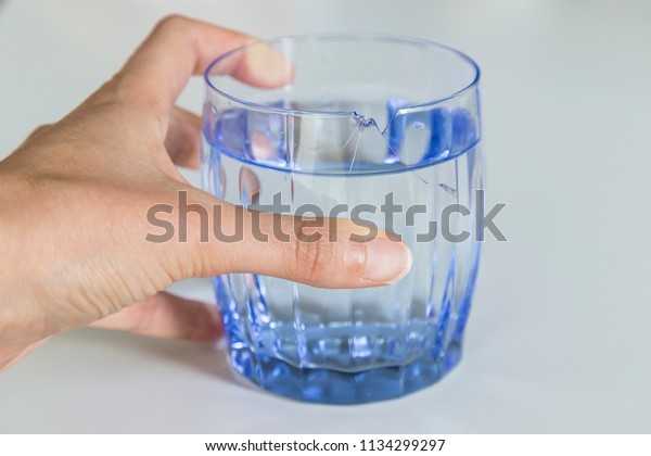 broken blue glass and hand on the white\
background.Injury due to glass breakage.damages of drinking water\
with broken glass.