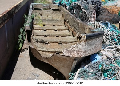 Broken Boat. An Old Broken Boat Thrown Into A Garbage Pile On The Side Of A Dock. Old Broken Boats Are Of No Use To Fishermen Or People. Broken Boats Are Dangerous And Can Easily Sink In The Ocean.