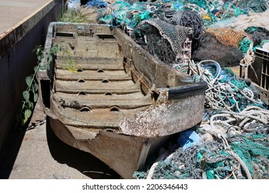 Broken Boat. An Old Broken Boat Thrown Into A Garbage Pile On The Side Of A Dock. Old Broken Boats Are Of No Use To Fishermen Or People. Broken Boats Are Dangerous And Can Easily Sink In The Ocean.