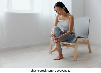 Broken Bone In Leg. Unhappy Sad Suffering Tanned Beautiful Young Asian Woman Touch Injury From Training Knee At Home Interior Living Room. Injuries Poor Health Illness Concept. Cool Offer Banner