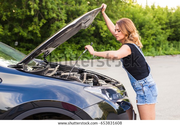 Broken car, accident and\
people concept - Woman open the car hood and broken automobile on\
the side.