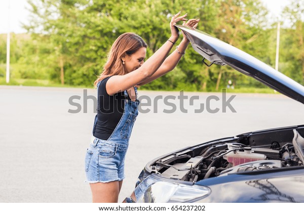 Broken car, accident and\
people concept - Woman open the car hood and broken automobile on\
the side.