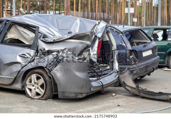 Broken car after a traffic accident in the parking\
lot of a repair station. Car body damage workshop outdoors. Sale of\
insurance cars. Accident on the street, car after a collision in\
the city