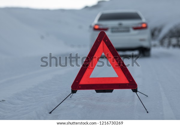 broken car and\
an emergency sign on a snowy\
road