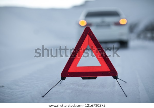 broken car and
an emergency sign on a snowy
road