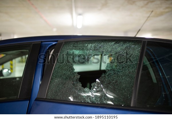Broken car glass window from thief. Car robbery in\
garage parking. 