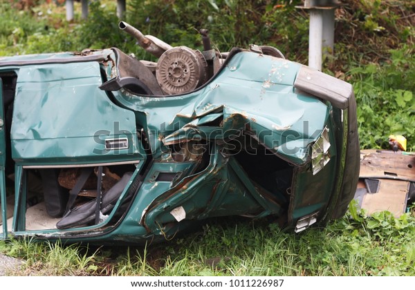 The broken car lies upside\
down.