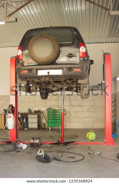 Broken\
car lifted on the lift in the auto service\
station