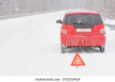 Broken Car On Snowy Road. Red Triangle Warning Sign For Emergency Stop. Snow And Blizzard, Winter Driving Hazard.