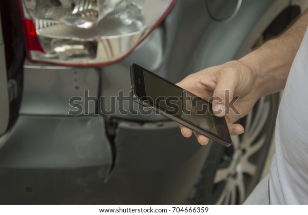 A broken car, the owner who stands nearby, and\
dials an insurance numberThe car crashed and the owner tries to\
call for helpThe car after the accident, the host in indignation\
calls the police