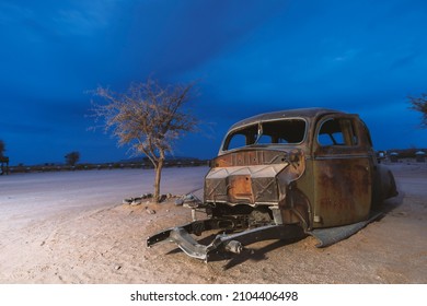 Broken Car Remains In Desert By Twilight In Namibia