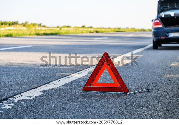Broken car at roadside. Red warning triangle\
at foreground
