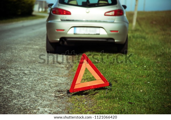A broken car and warning\
triangle