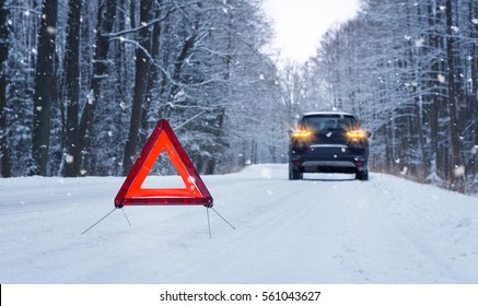 Broken Car And Warning Triangle On The Snowy Winter Road