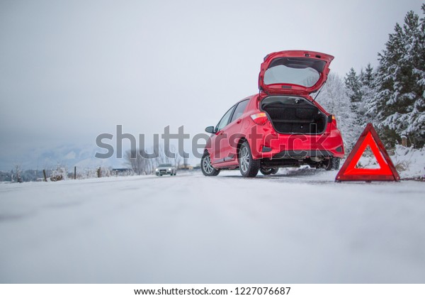Broken car and warning triangle on the snowy\
winter road\
