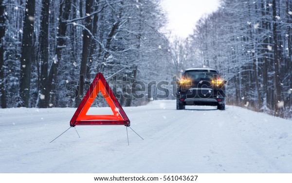 Broken\
car and warning triangle on the snowy winter\
road