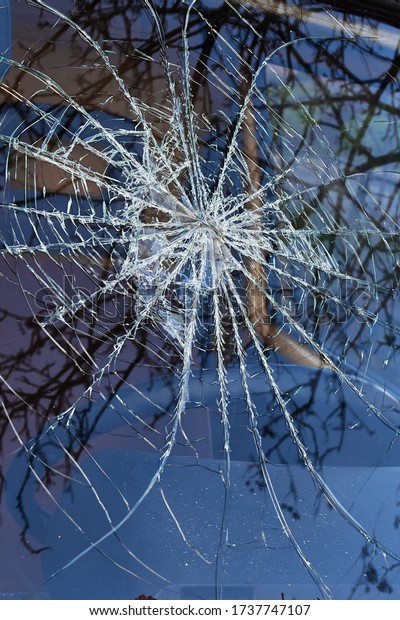 a broken car\
windshield like a spider\'s\
web