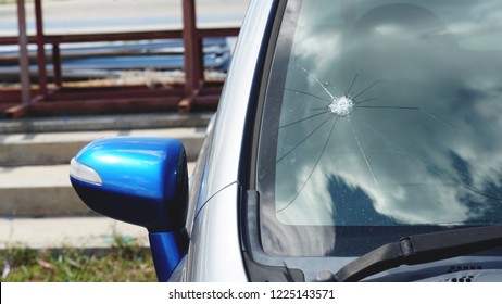 Broken car windshield. Stones on a dirty road from under the wheels at a speed smash car glass. Criminal incidents. Vandals, hooligans mutilated the car, smashed the windshield