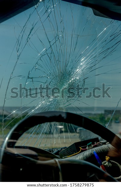 Broken car windshield. Web of radial cracks, crack\
on triple windshield. Broken windshield car, damaged glass with\
traces of an oncoming stone on road or trace of downed pedestrian\
or animal on road