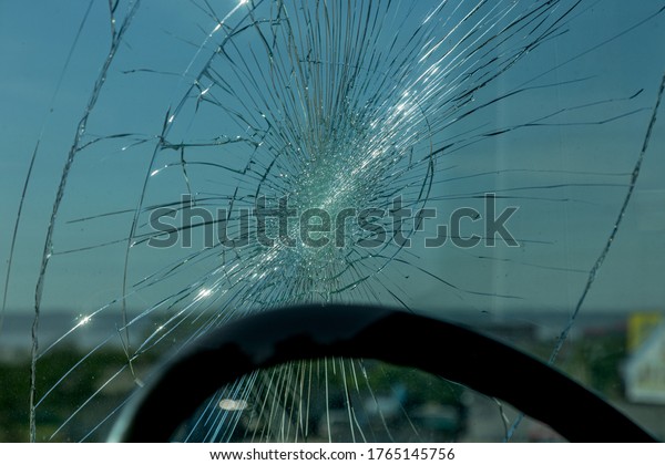 Broken car windshield. Web of radial cracks, crack\
on triple windshield. Broken windshield car, damaged glass with\
traces of an oncoming stone on road or trace of downed pedestrian\
or animal on road