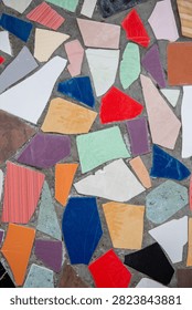Broken ceramic tile mosaic pattern featuring bright multicolored pieces on wall surface. Real Photo.