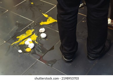 Broken Chicken Eggs On The Kitchen Floor. Dropped Fresh Food On The Floor. Broken Egg Shell On A Dark Background