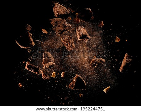 Broken chocolate cookies explosion on black background