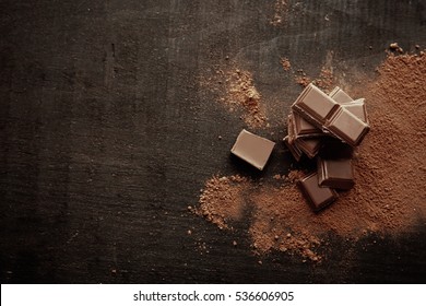 Broken chocolate pieces and cocoa powder on wooden background - Shutterstock ID 536606905