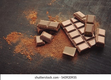 Broken chocolate pieces and cocoa powder on wooden background - Shutterstock ID 543920935